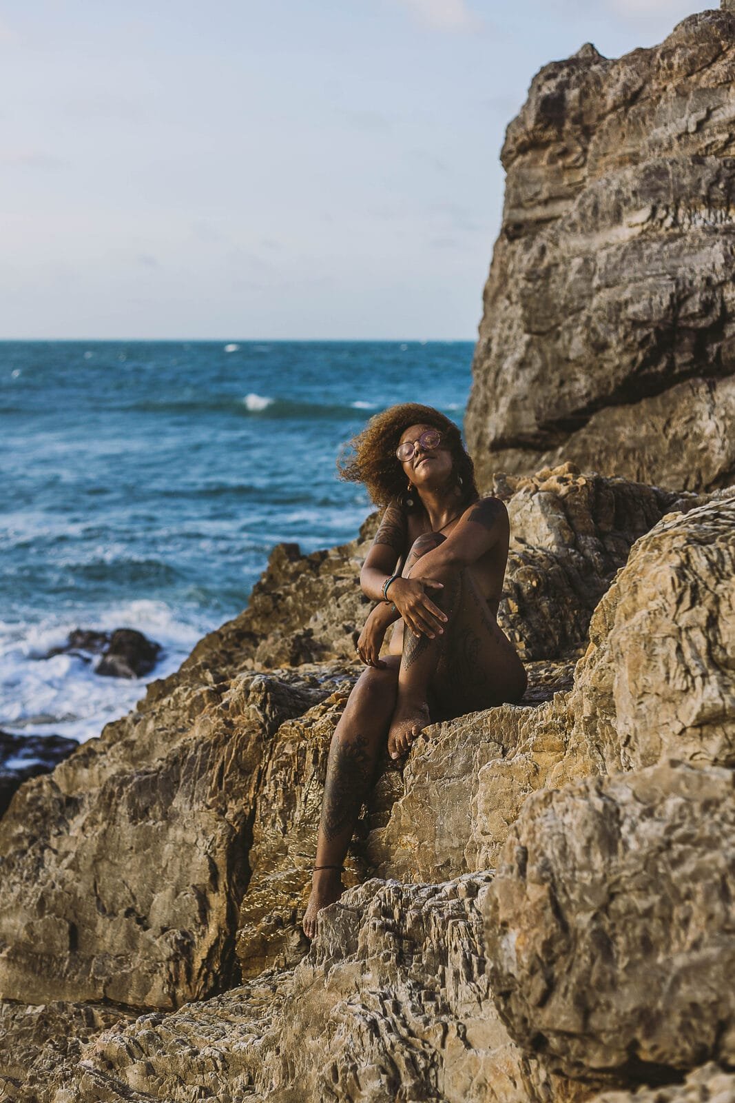 Chayenne sitting on a large rock by the sea in Jericoacoara