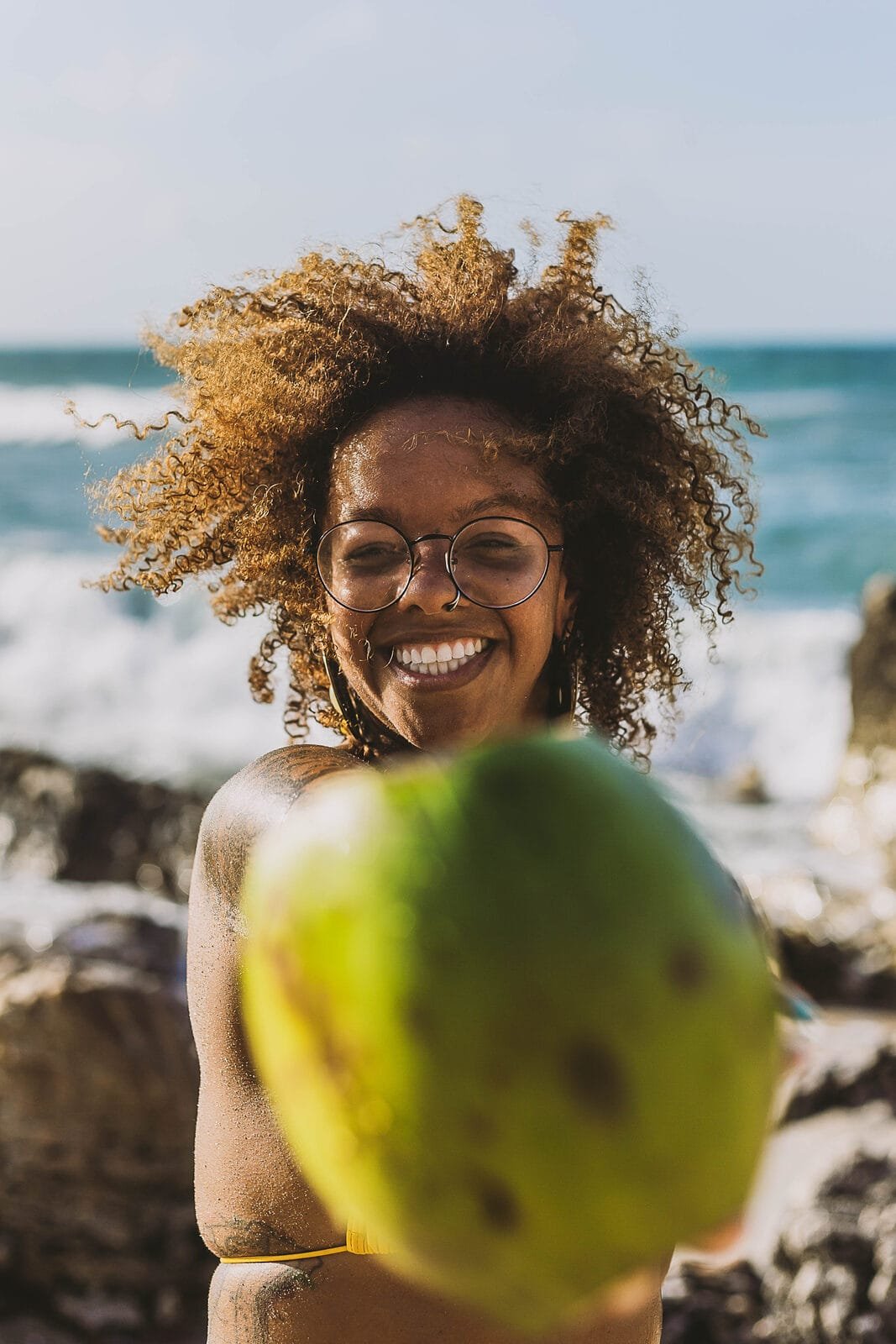Chayenne smiling on the beach in Jericoacoara, holding a green coconut