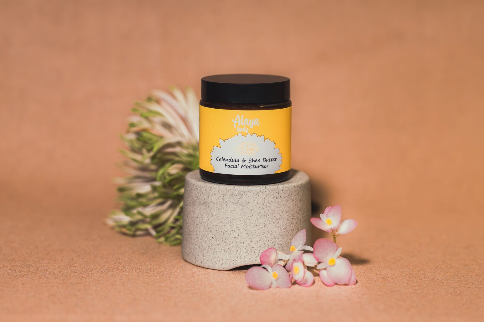 Alaya Body facial moisturiser photographed on a sandstone plinth