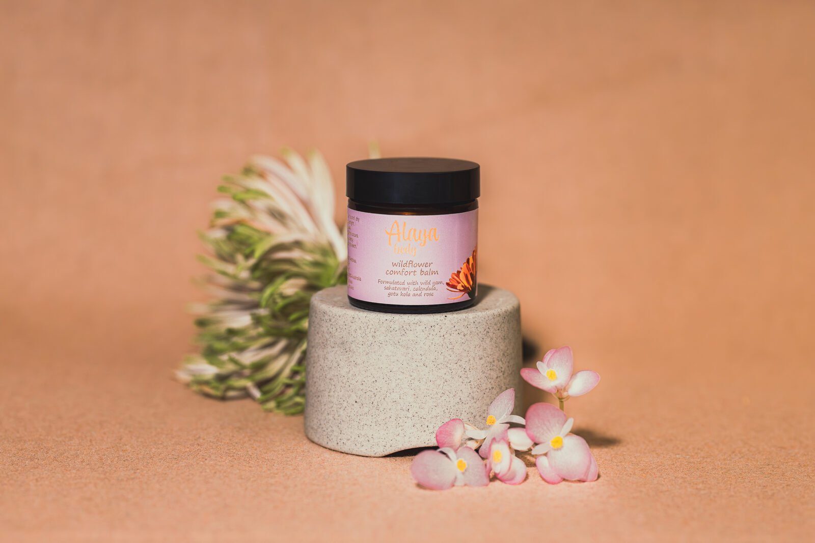 Alaya Body jar photographed on a sandstone plinth with native flowers